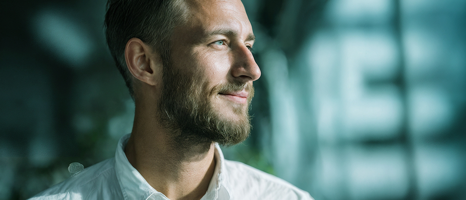 Happy_Investor Ein Mann blickt zufrieden aus dem Fenster